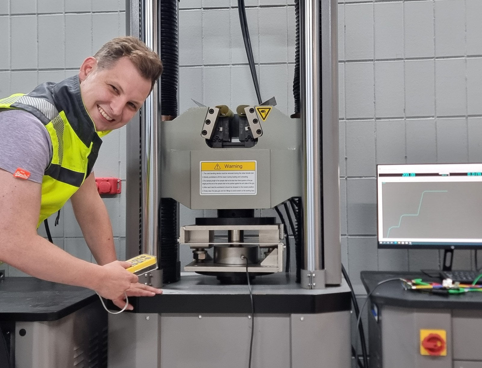 Mitarbeiter von octogon in Warnweste an der Prüfmaschine im Kalibrierlabor